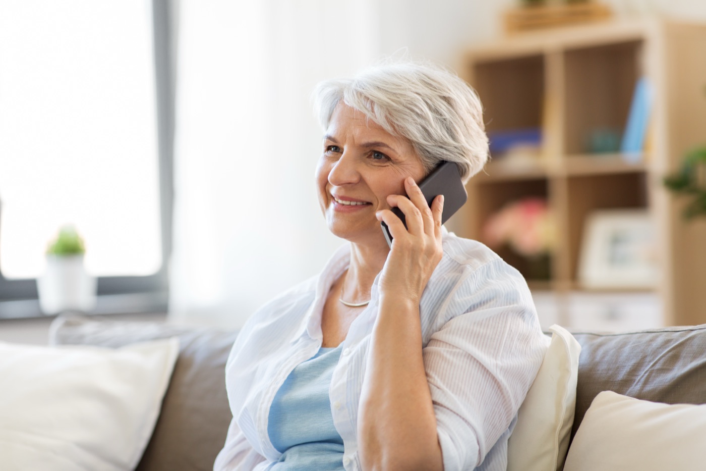A senior woman smiling during a friendly phone call at home