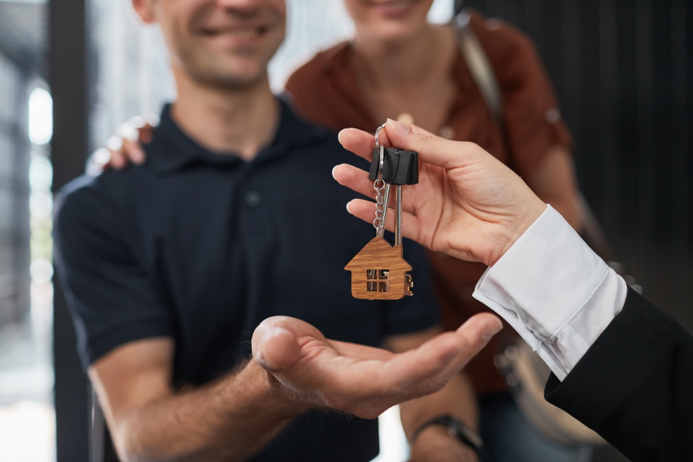 A real-estate professional handing house keys to a happy couple buying a new home